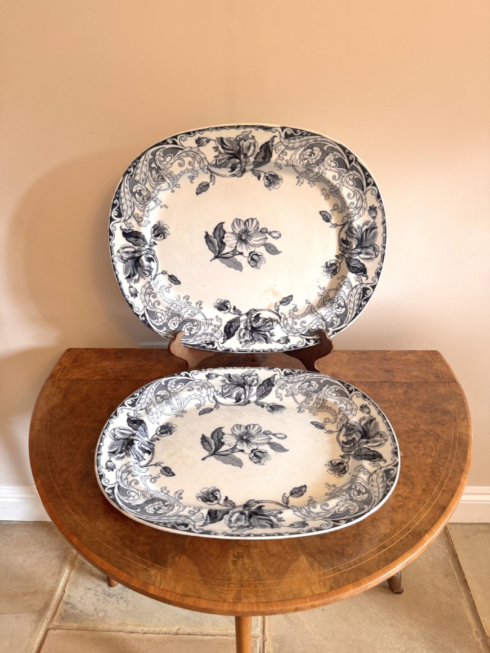 A pair of oval Victorian transferware ceramic meat platters decorated with dark blue floral patterns on an off-white background.