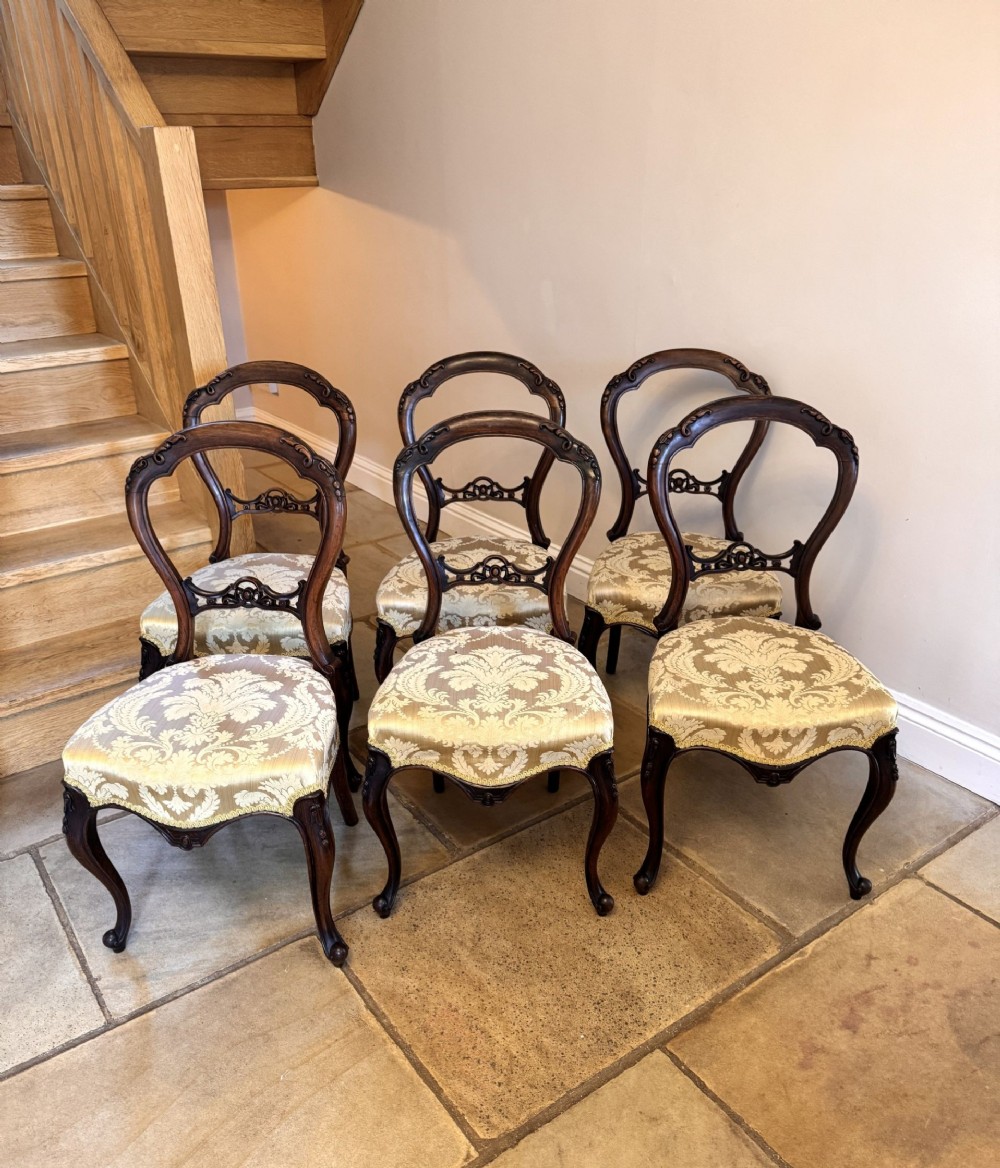 Set of six Victorian balloon back dining chairs crafted from carved dark rosewood with gold damask upholstered seats and cabriole legs.