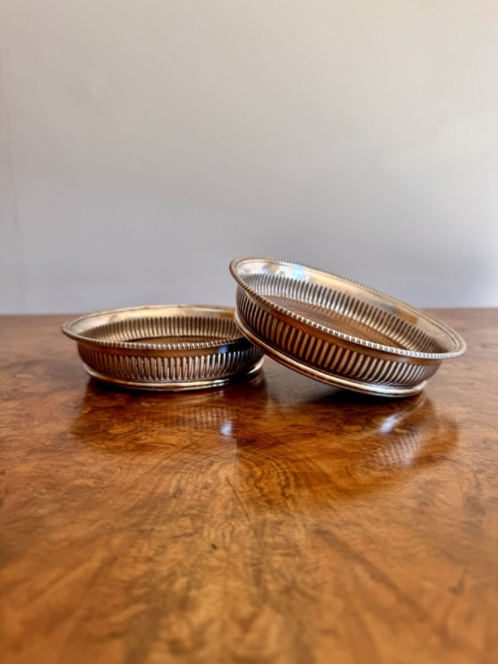 A pair of Victorian silver-plated wine coasters featuring fluted sides, beaded borders, and turned wooden bases.