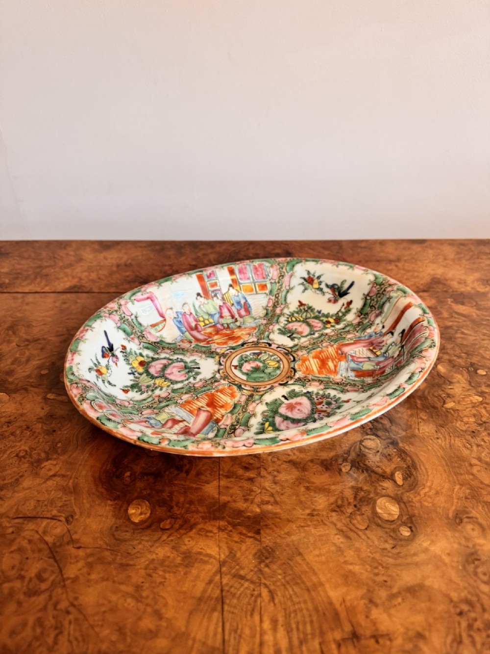 An oval 19th-century Chinese export porcelain dish painted with Rose Medallion panels featuring figures, birds, and flowers in pink and green enamels.