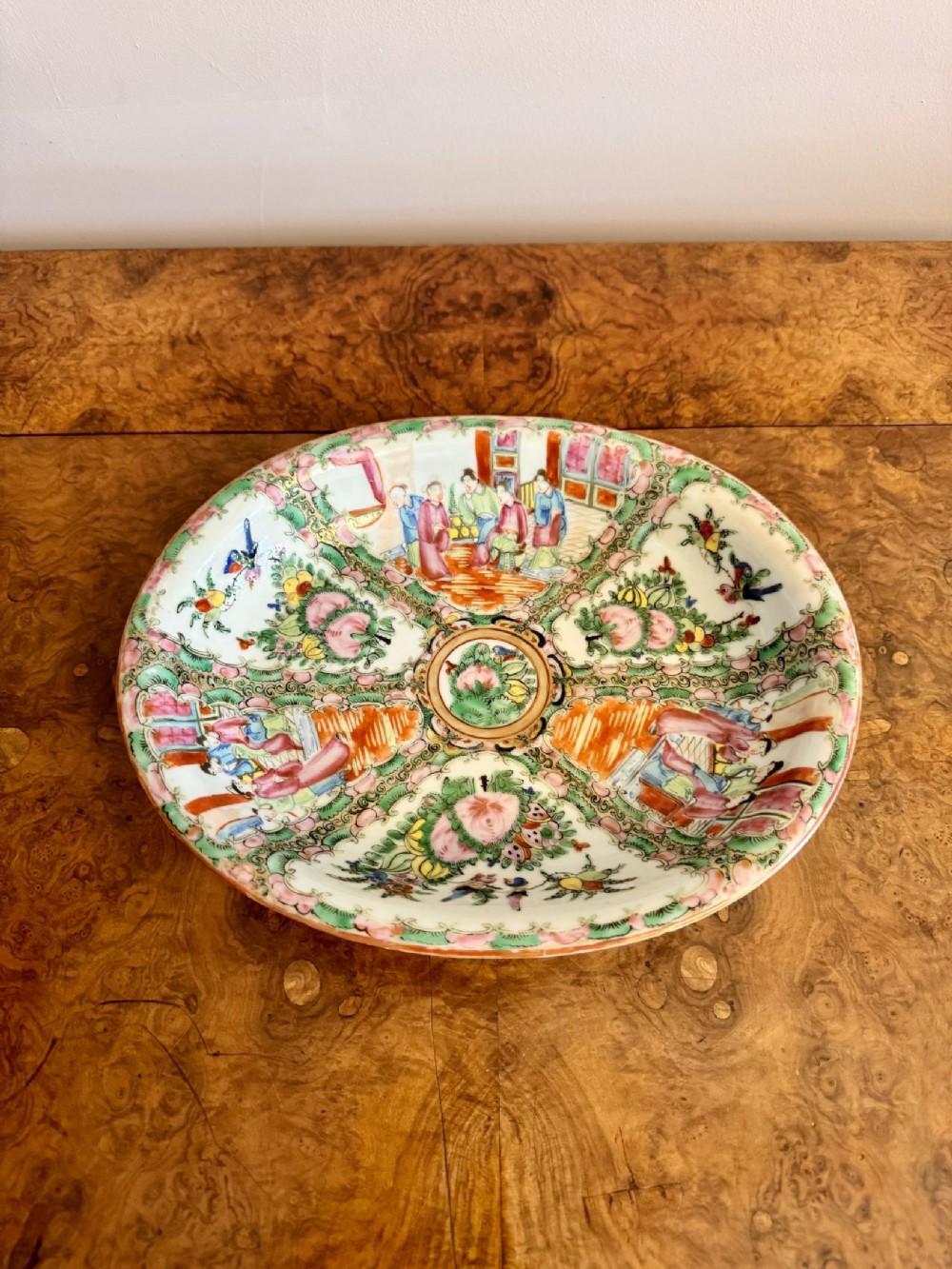 An oval 19th-century Chinese export porcelain dish painted with Rose Medallion panels featuring figures, birds, and flowers in pink and green enamels. View IV