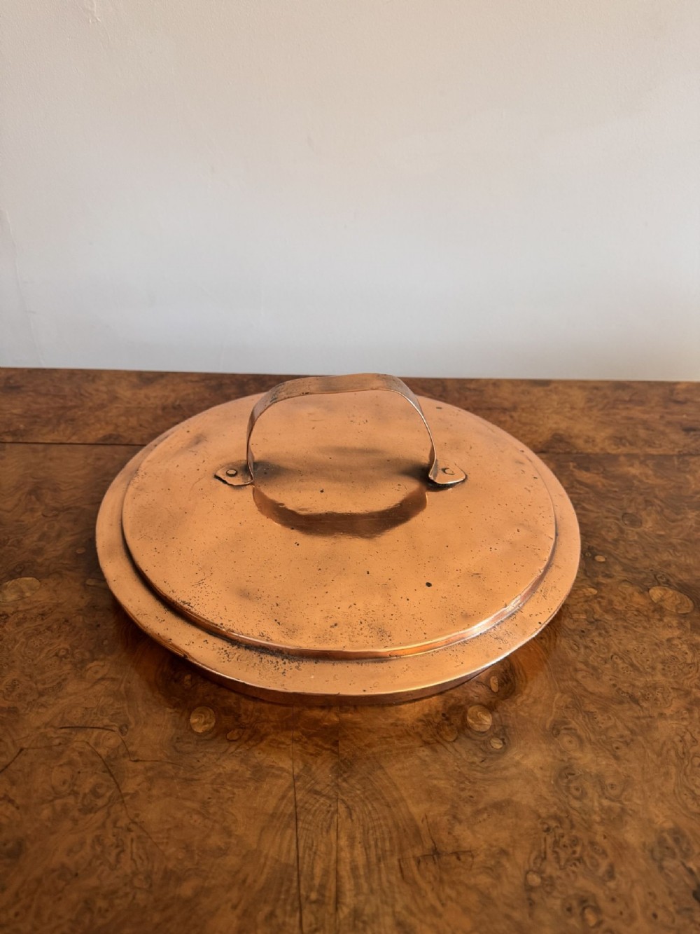 A large round hand-hammered copper pot with a fitted copper lid and a dark iron swing handle. View IV