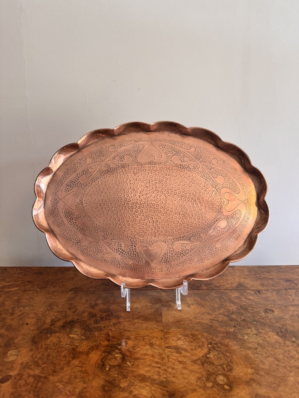 An oval antique Art Nouveau copper tray with a scalloped edge and hand-hammered organic scroll motifs.