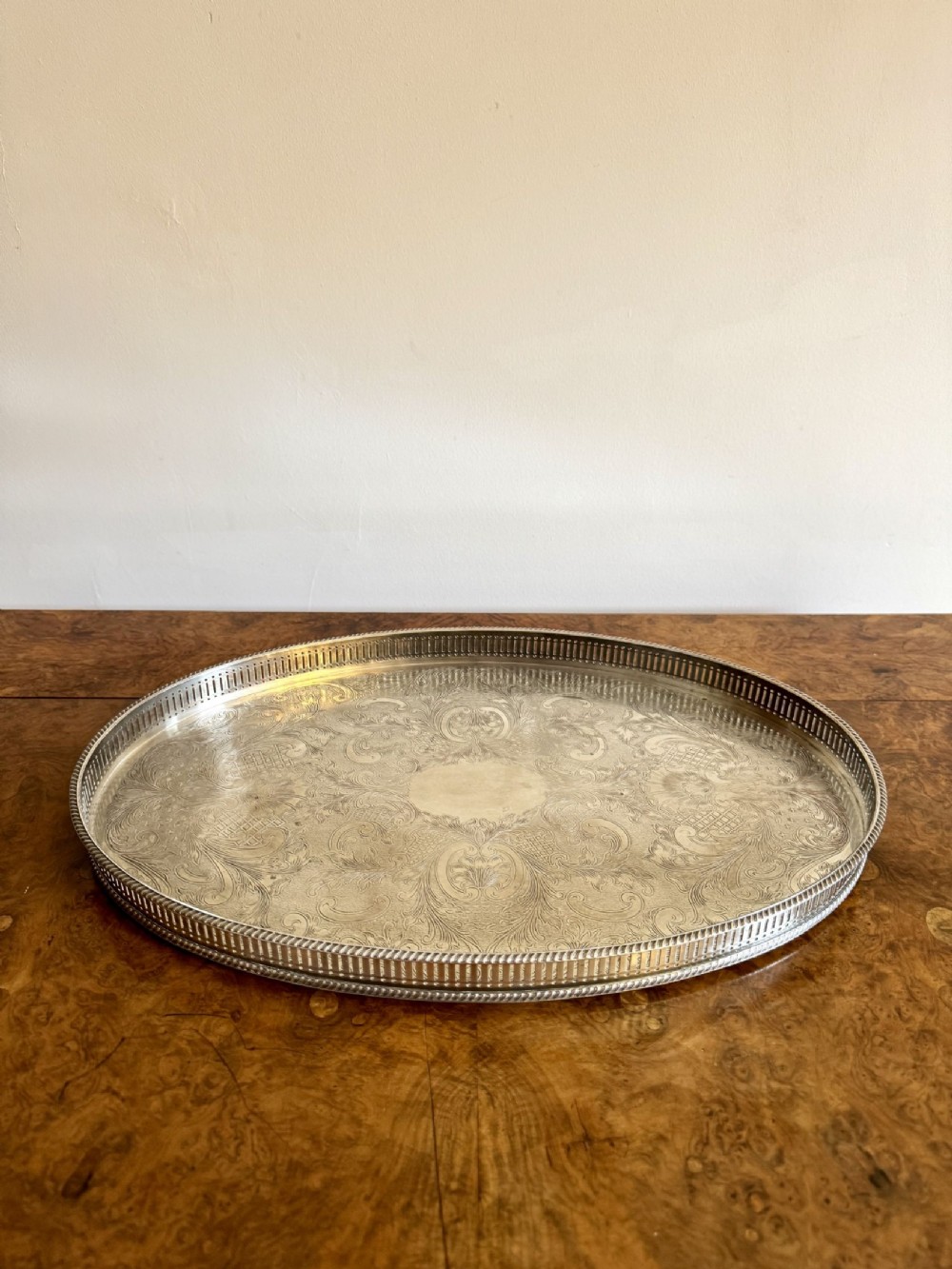 An oval Edwardian silver plated tray featuring a pierced gallery rim and an engraved foliate surface design with a central cartouche.