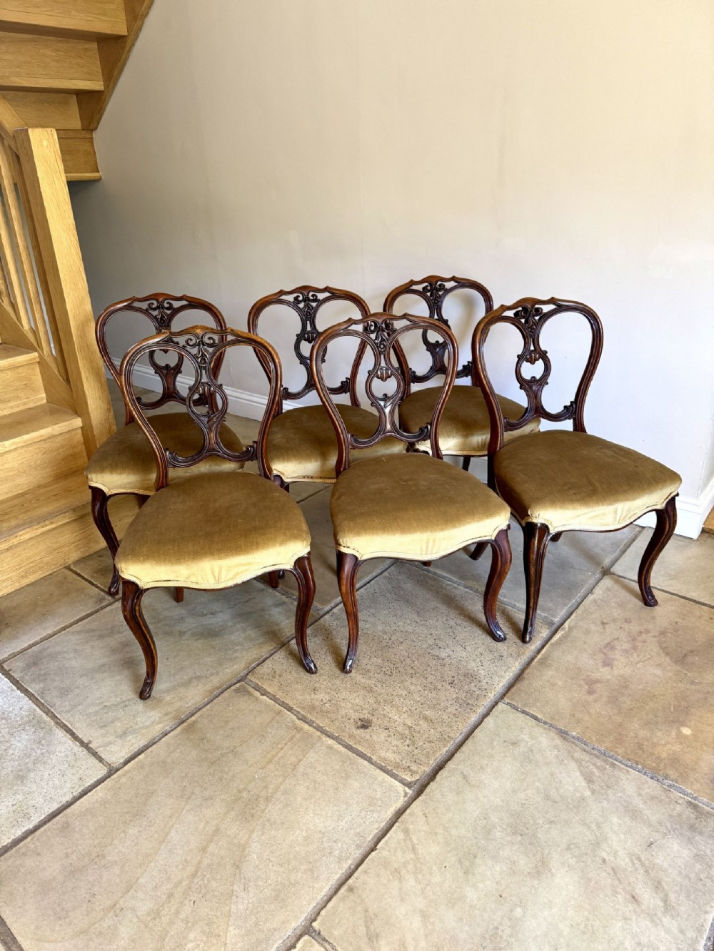 A set of six Victorian walnut dining chairs with carved balloon-style pierced backs, curved cabriole legs, and gold velvet upholstered seats.