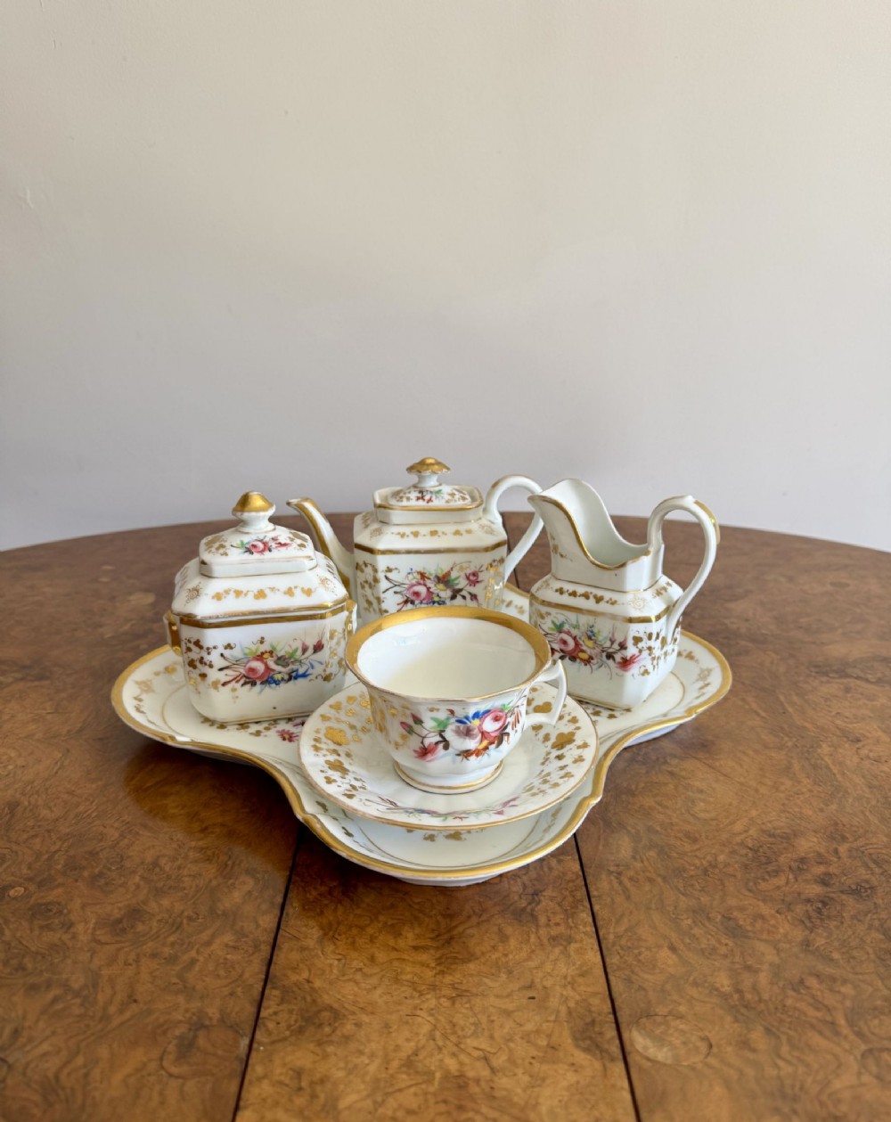 A nineteenth-century white porcelain breakfast set decorated with hand-painted floral motifs and gilded rims, presented on a fitted shaped tray.