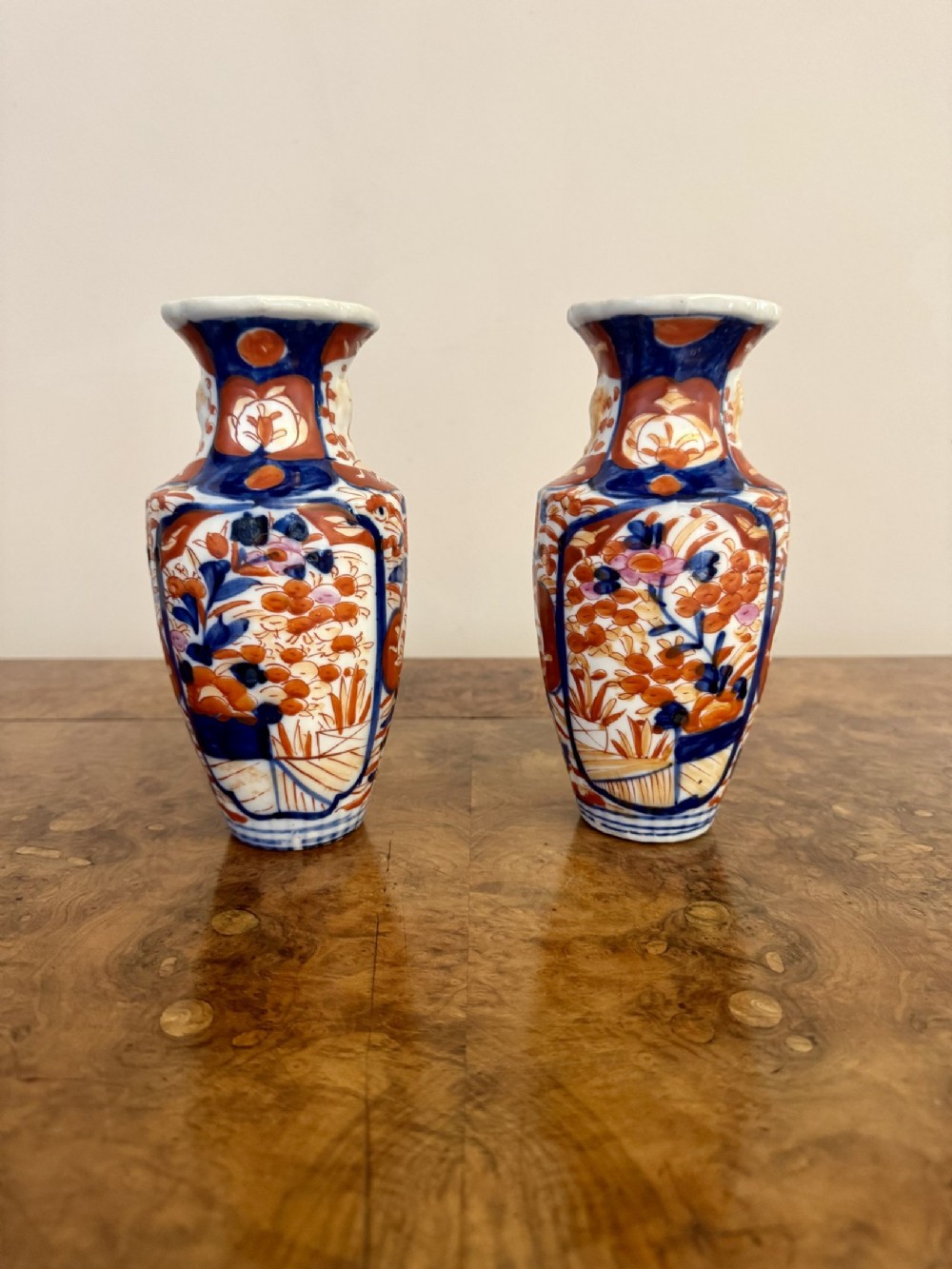 A pair of small antique Japanese Imari porcelain vases painted with cobalt blue, iron red, and orange floral motifs.