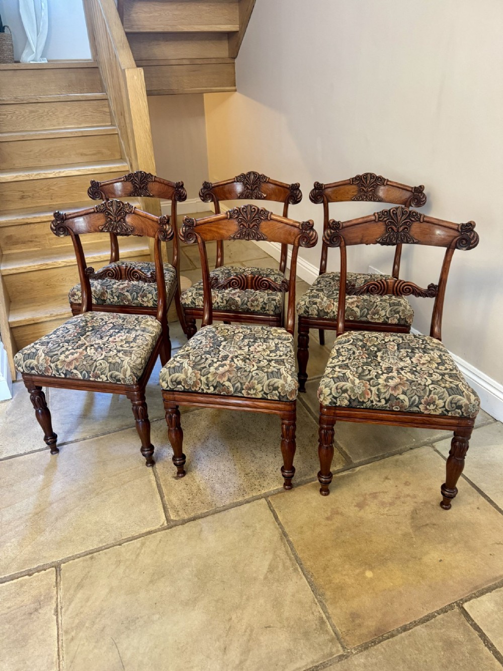 A set of six Regency rosewood dining chairs with carved cresting rails, turned legs, and floral tapestry seats.