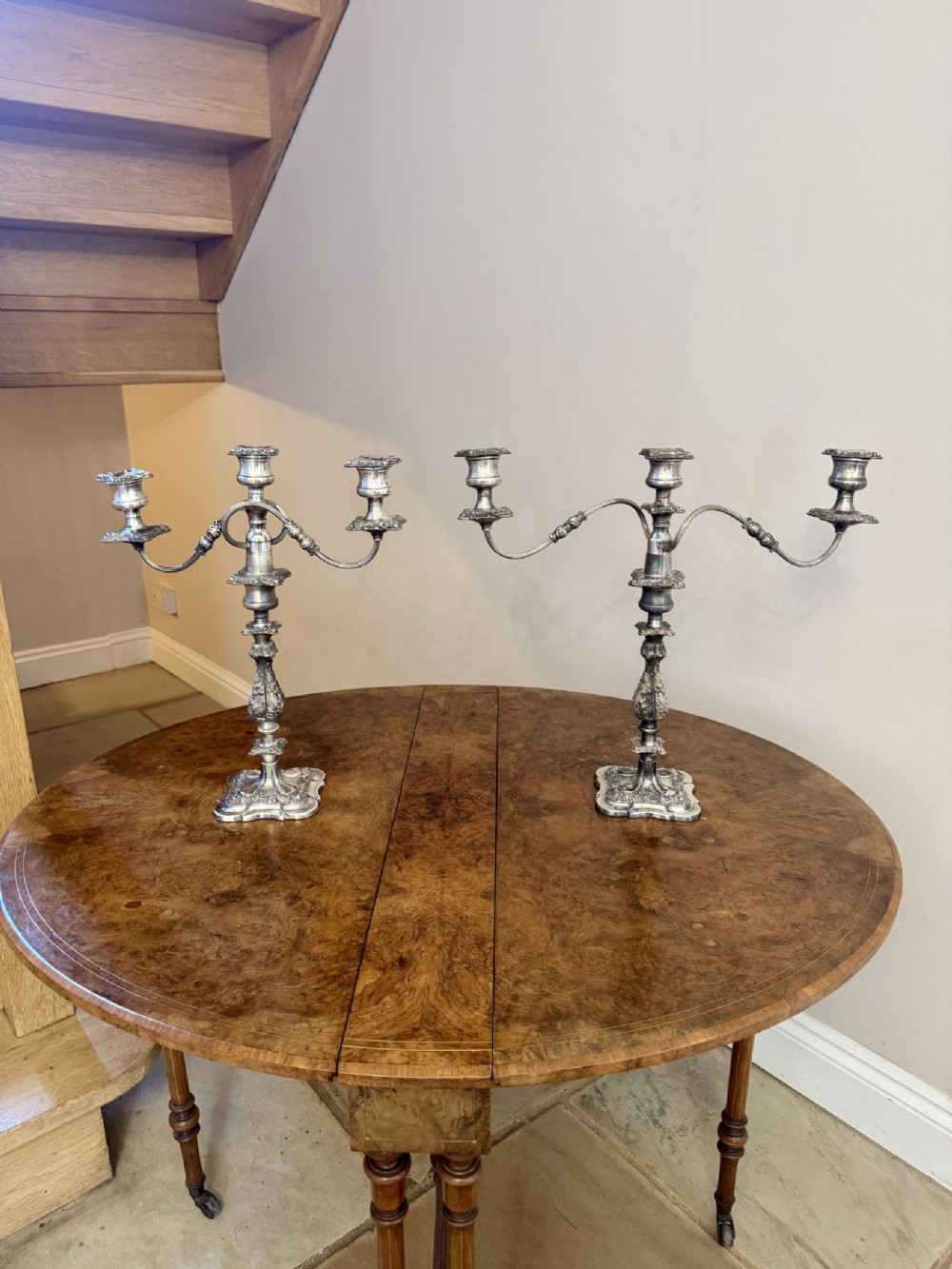A pair of Victorian silver-plated three-light candelabras featuring curved branches, ornate chased bases, and detailed sconces.