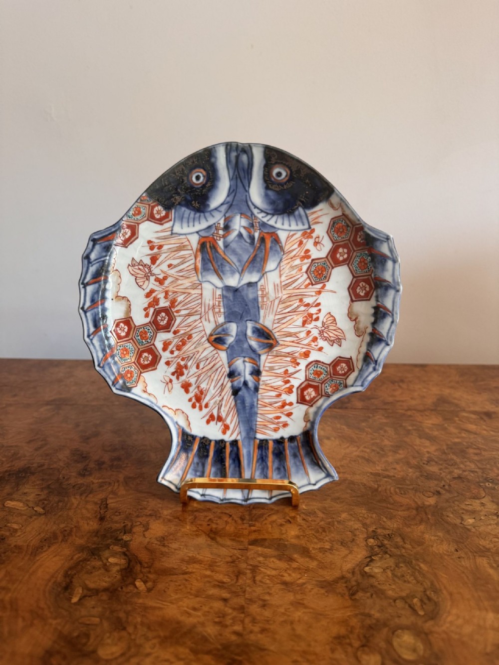 A Japanese Imari porcelain plate formed in the shape of a flatfish with blue, rust red, and orange hand-painted decoration.