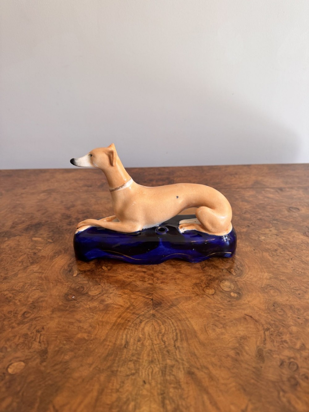 A Victorian Staffordshire earthenware inkwell featuring a tan reclining greyhound on a deep cobalt blue base.