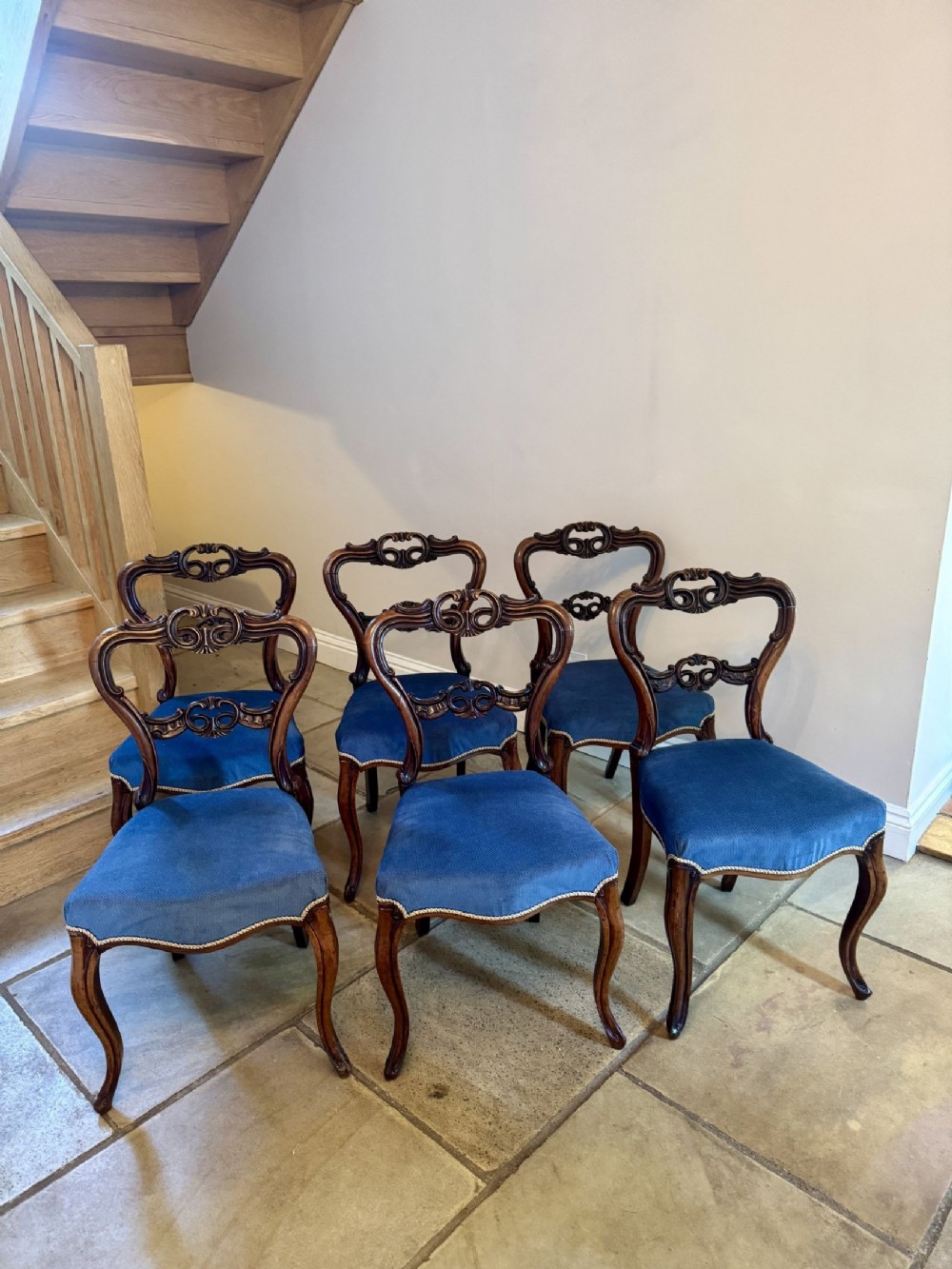 A set of six Victorian rosewood dining chairs featuring carved balloon back frames, cabriole front legs, and blue fabric upholstered seats.