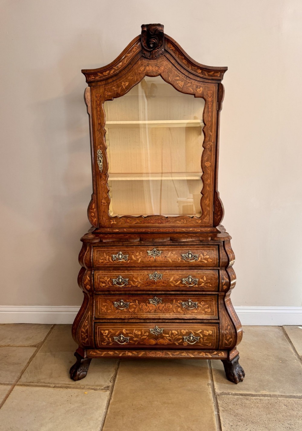 An eighteenth-century Dutch walnut display cabinet with intricate floral marquetry inlay, featuring an arched glazed upper section above a curved bombe base with four drawers.