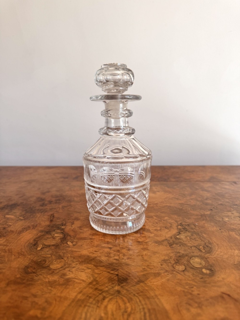 A clear Edwardian cut glass decanter featuring a diamond cut body and a fitted faceted glass stopper.