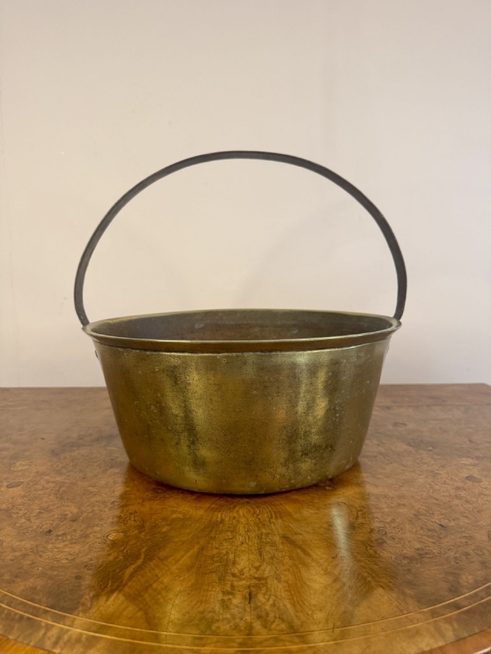A Victorian heavy brass jam pan featuring a rolled rim and a curved dark iron swing handle.