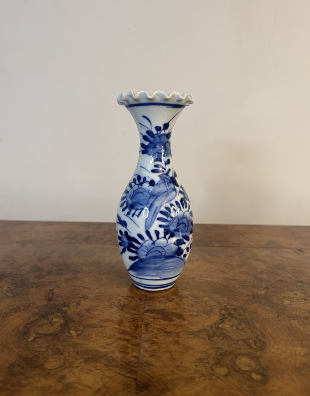 A Japanese porcelain baluster vase decorated with hand-painted cobalt blue floral motifs and featuring a frilled rim.