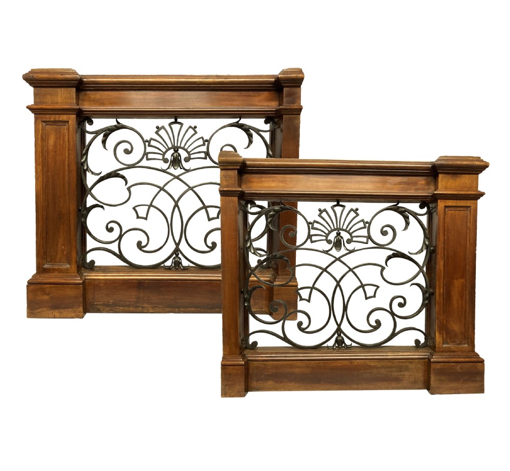 A pair of wooden-framed architectural balustrades featuring central wrought iron panels with scrolled patterns and fan motifs.