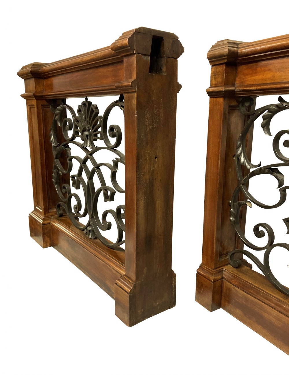 A pair of wooden-framed architectural balustrades featuring central wrought iron panels with scrolled patterns and fan motifs. View X
