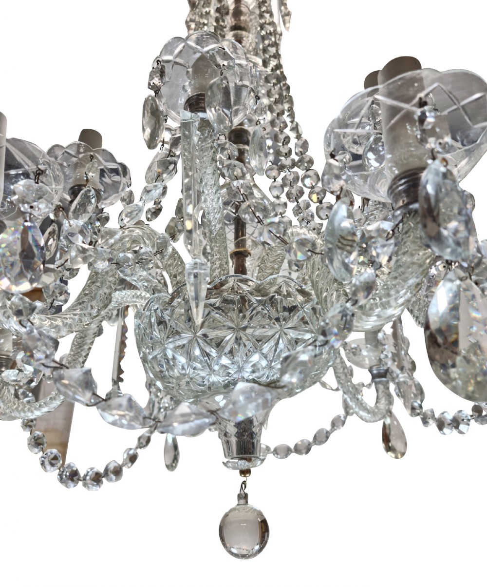 An English twelve-light cut glass chandelier featuring tiered glass arms, faceted crystal drops, and cascading bead swags. View IV
