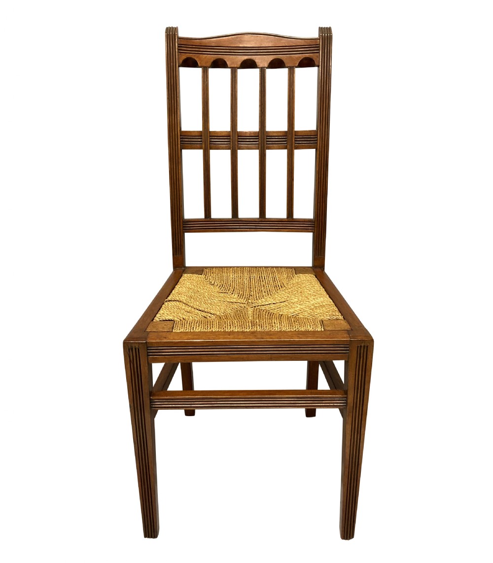 A set of four English Aesthetic Movement mahogany dining chairs featuring vertical spindle backs and natural rush woven seats. View II