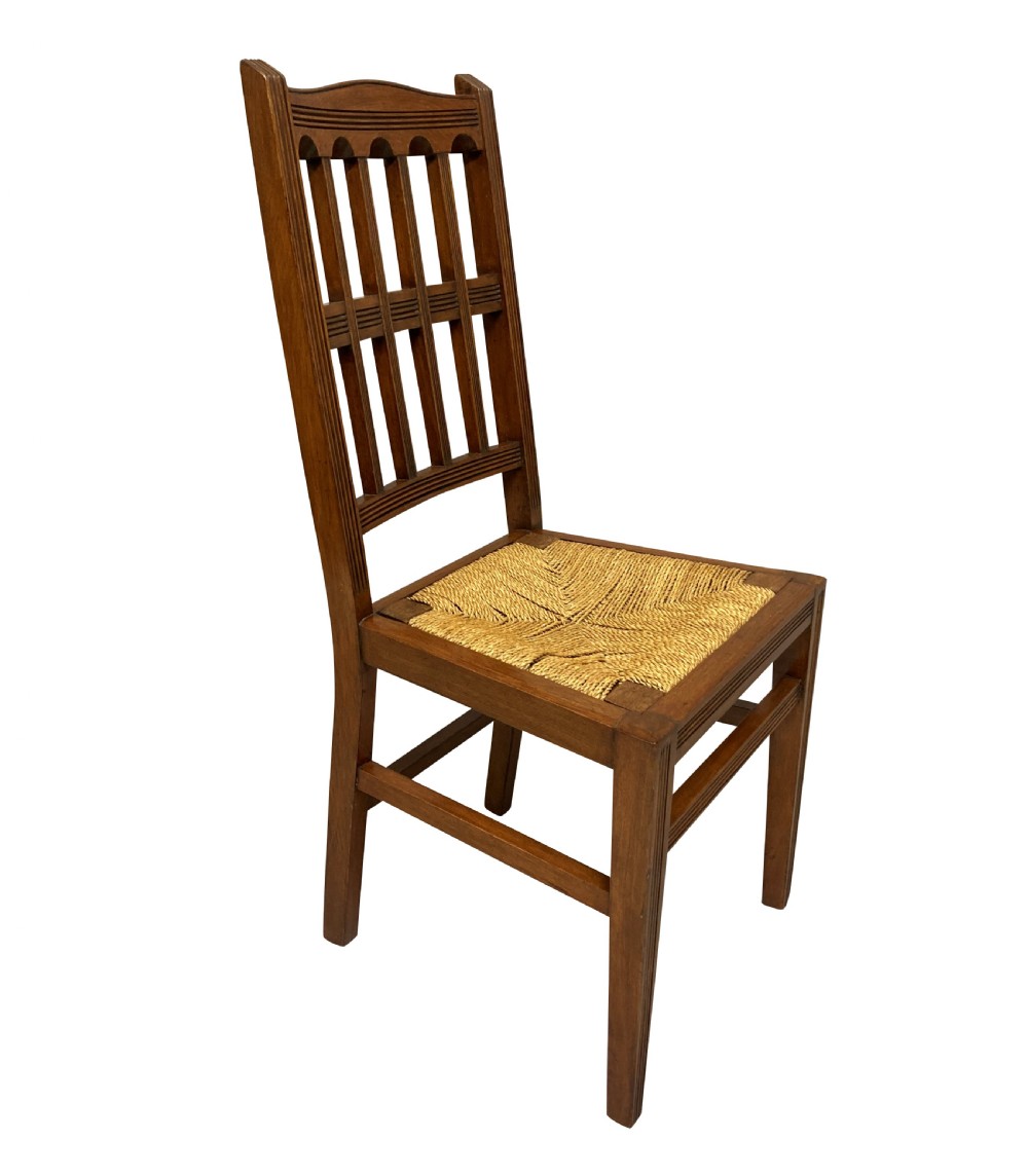 A set of four English Aesthetic Movement mahogany dining chairs featuring vertical spindle backs and natural rush woven seats. View V