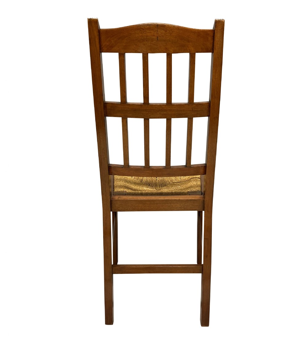 A set of four English Aesthetic Movement mahogany dining chairs featuring vertical spindle backs and natural rush woven seats. View VI