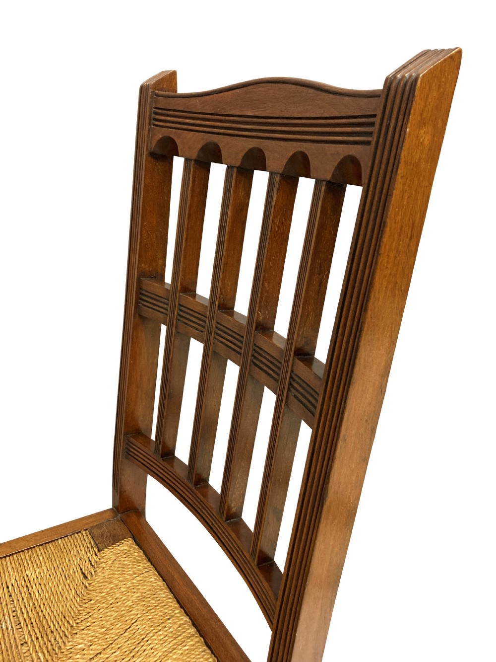 A set of four English Aesthetic Movement mahogany dining chairs featuring vertical spindle backs and natural rush woven seats. View VIII