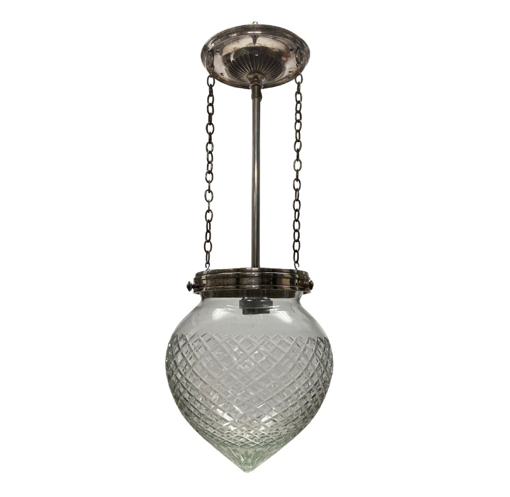 An Edwardian clear cut glass pendant light featuring a diamond-patterned acorn shade suspended by metal chains and a central rod from a fluted ceiling rose.