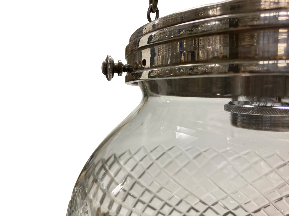 An Edwardian clear cut glass pendant light featuring a diamond-patterned acorn shade suspended by metal chains and a central rod from a fluted ceiling rose. View II