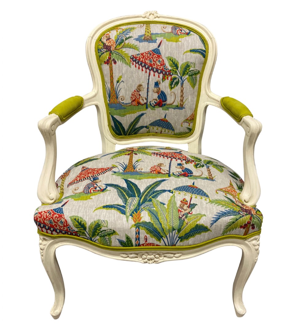 A pair of cream painted Louis XV style armchairs featuring carved cresting, cabriole legs, and upholstery with a monkey and palm tree pattern. View II