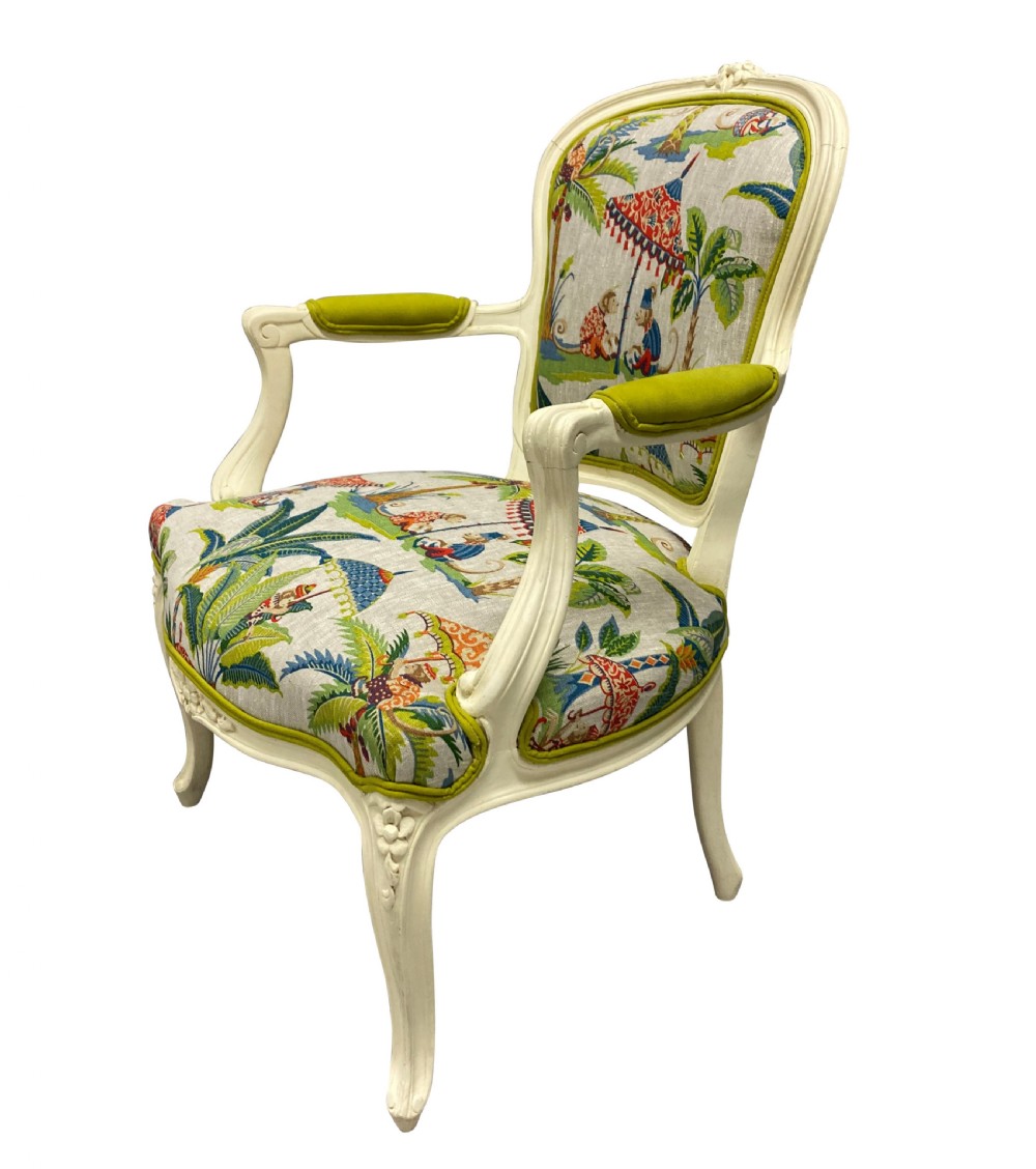 A pair of cream painted Louis XV style armchairs featuring carved cresting, cabriole legs, and upholstery with a monkey and palm tree pattern. View IV
