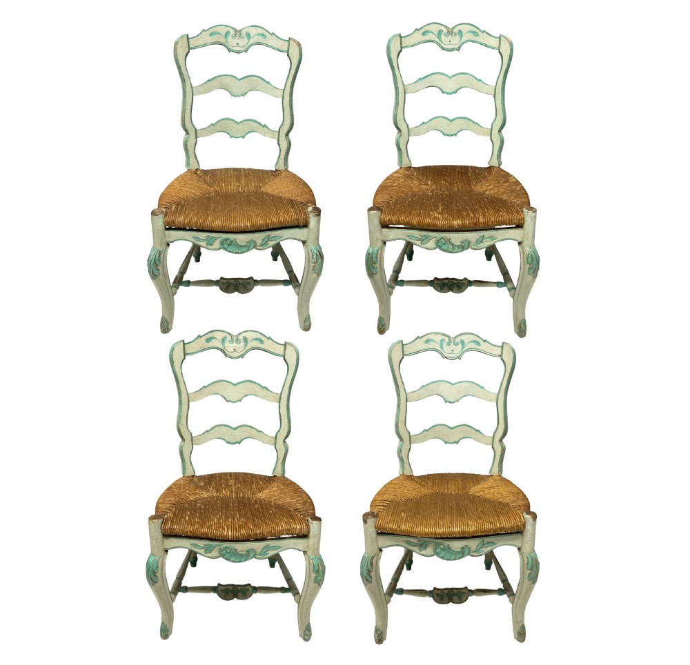 A set of four pale green painted Swedish dining chairs featuring carved wavy ladder backs, woven rush seats, and cabriole legs.