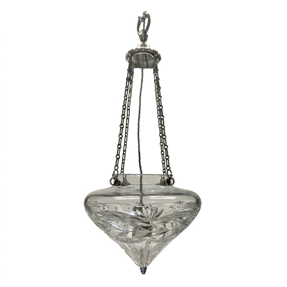 An Edwardian cut glass pendant light with starburst and geometric facets, suspended by three metal chains from a top gallery hook.