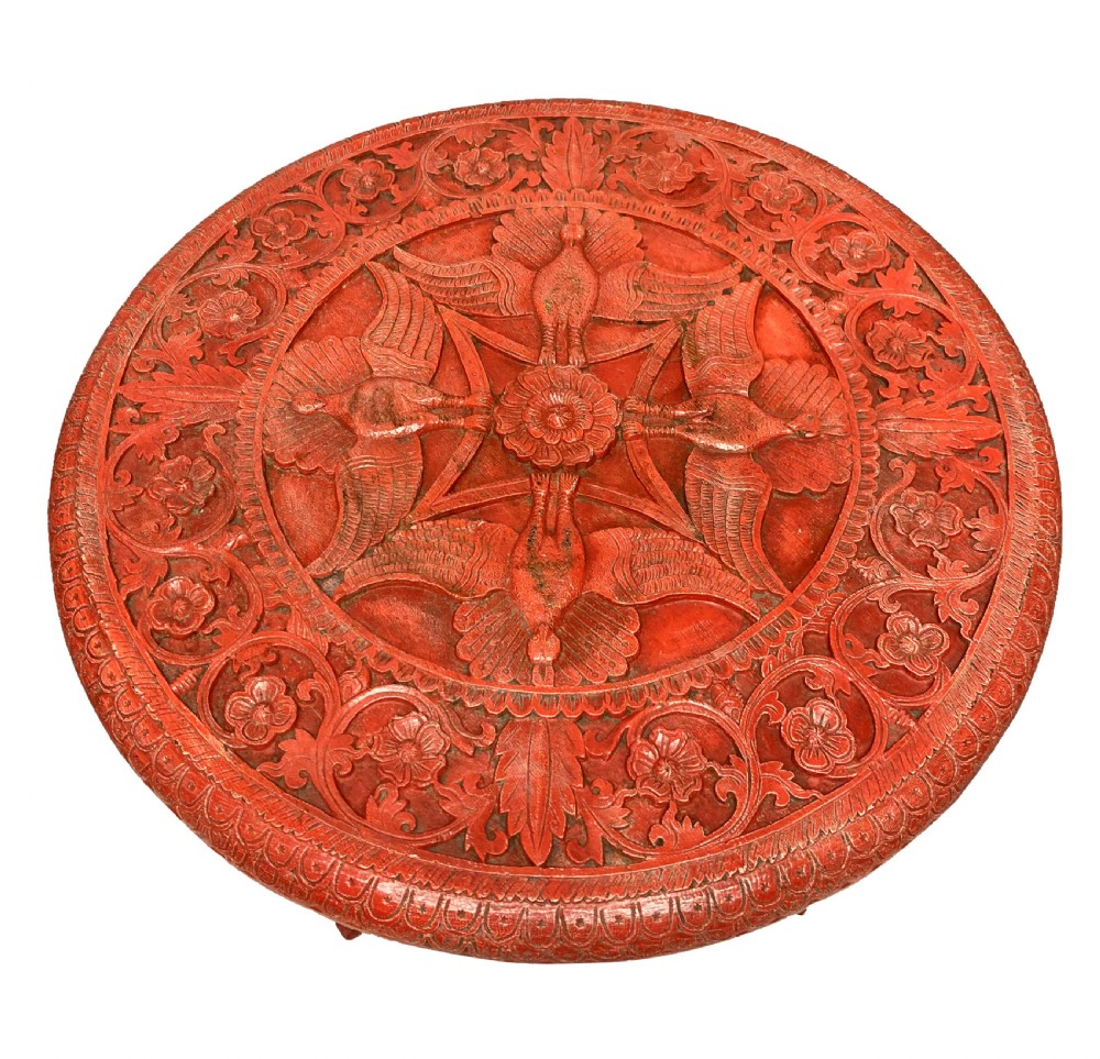 A circular red Chinese side table featuring carved cinnabar lacquered relief patterns on the top and three legs shaped as dragons. View VIII
