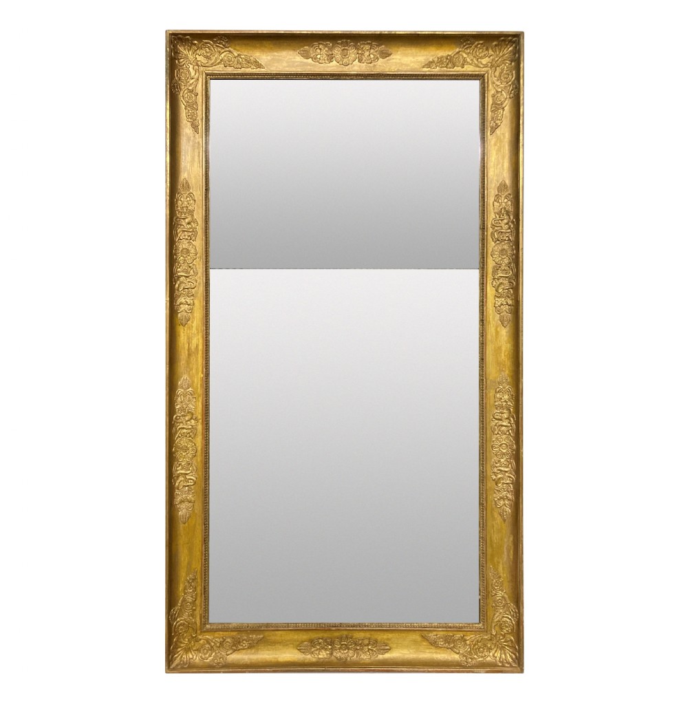 A large rectangular French Napoleon III giltwood mirror featuring relief floral carvings along the frame and a horizontal split glass plate.