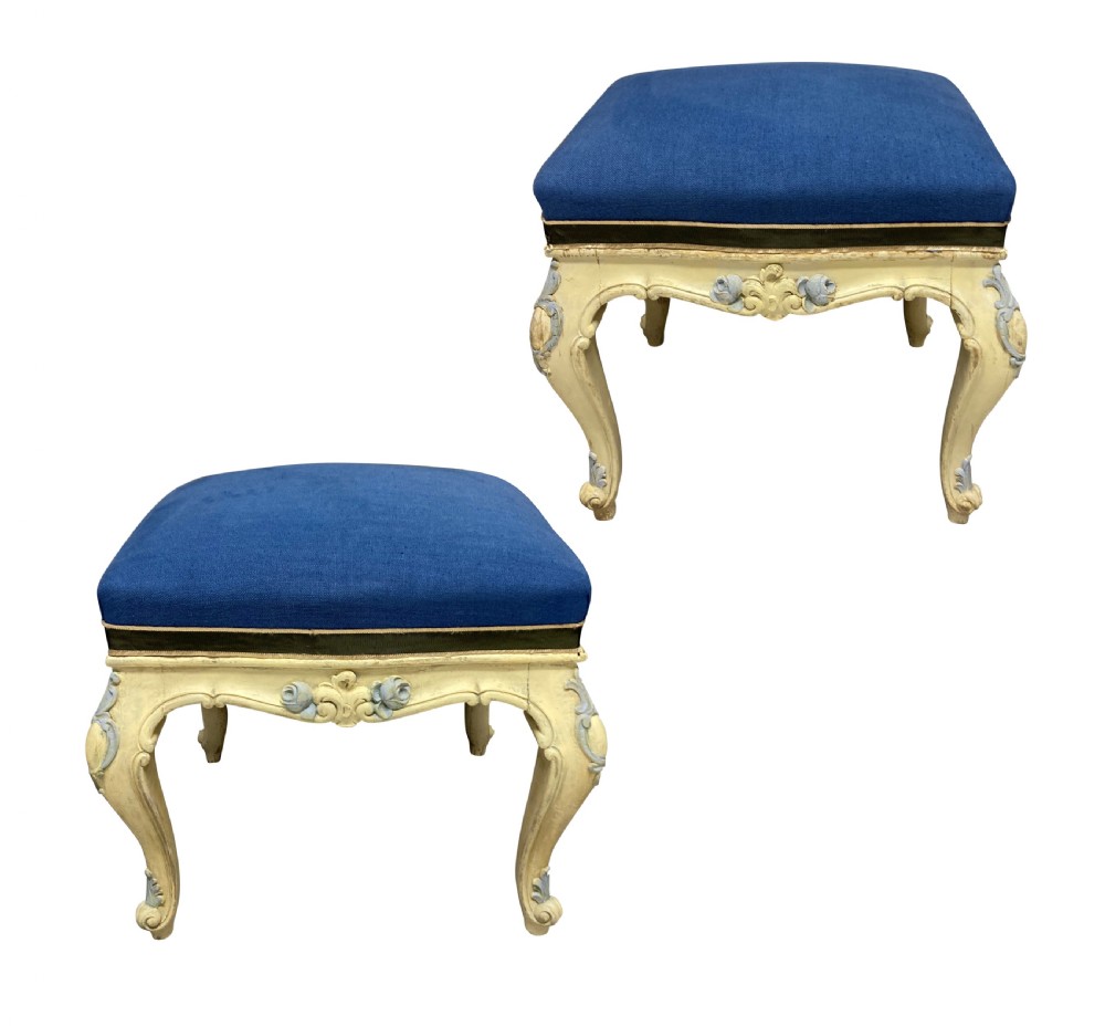 A pair of Louis XV style stools featuring cream and light blue painted carved wooden bases with cabriole legs and royal blue upholstered seats.