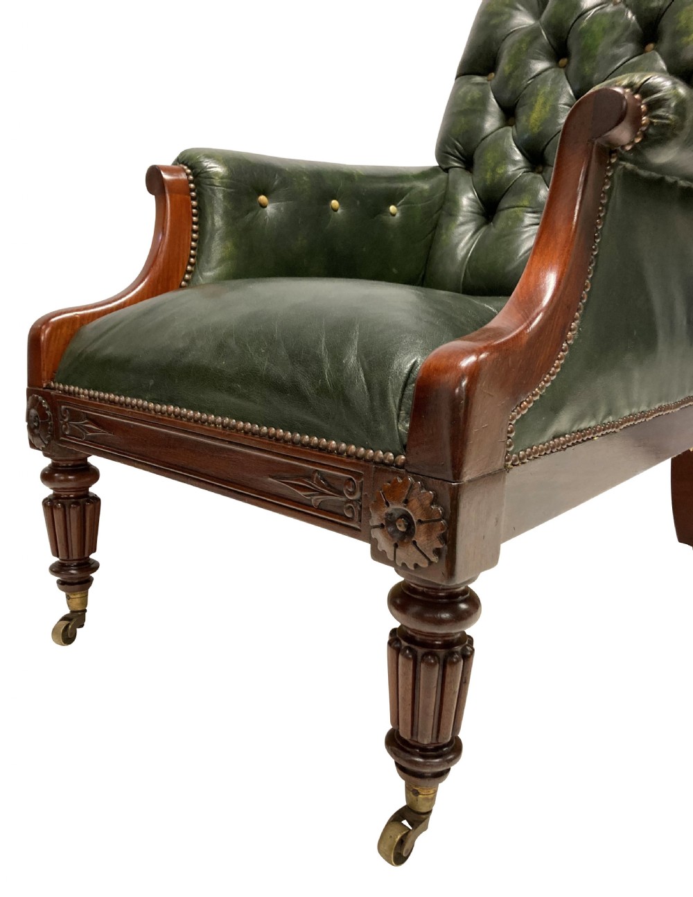 An antique William IV library chair upholstered in deep-buttoned green leather with brass stud trim and carved mahogany legs on brass castors. View II