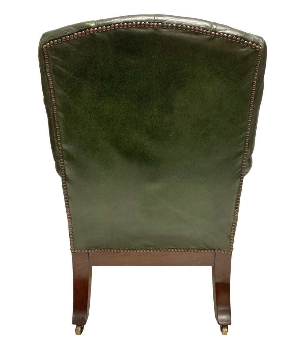 An antique William IV library chair upholstered in deep-buttoned green leather with brass stud trim and carved mahogany legs on brass castors. View VI