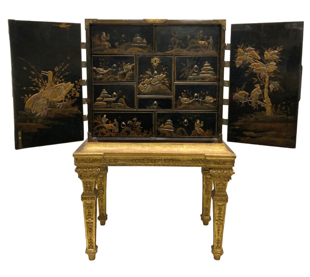 A two-door black japanned cabinet decorated with gold Chinoiserie scenes resting on a carved gilded wooden stand. View II