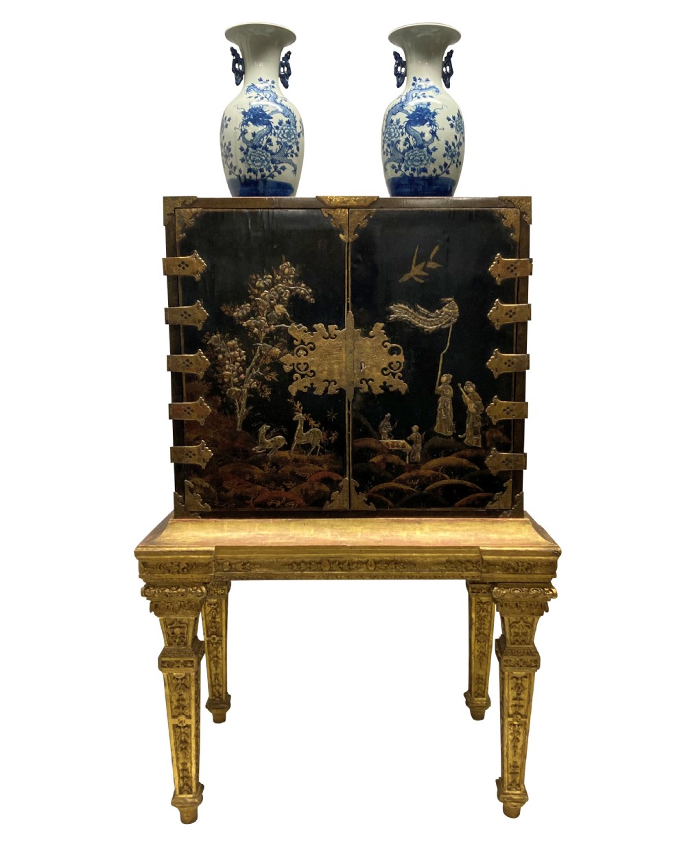 A two-door black japanned cabinet decorated with gold Chinoiserie scenes resting on a carved gilded wooden stand. View VII