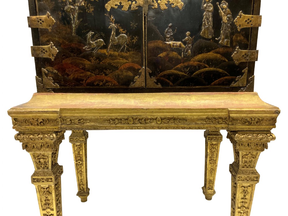 A two-door black japanned cabinet decorated with gold Chinoiserie scenes resting on a carved gilded wooden stand. View XII