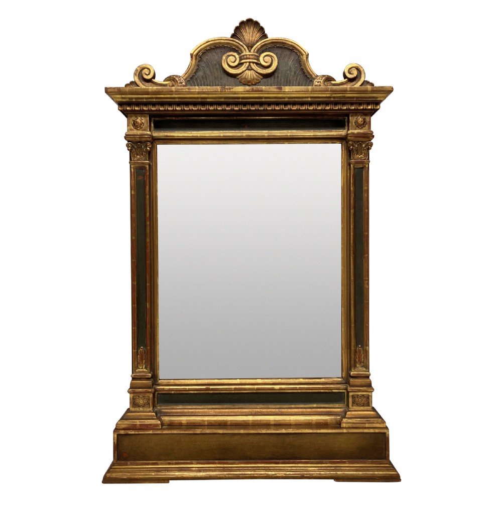 An Italian Renaissance giltwood tabernacle wall mirror featuring carved side pilasters, dark painted panels, and a cresting pediment with a central shell motif.