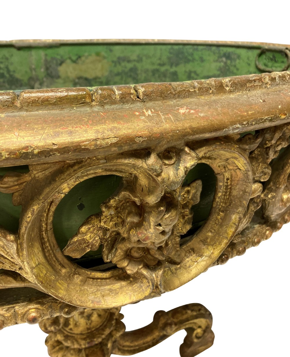 An early 19th-century carved giltwood circular jardiniere featuring scrollwork moulding, a green painted metal liner, and a sculpted tripod base. View II
