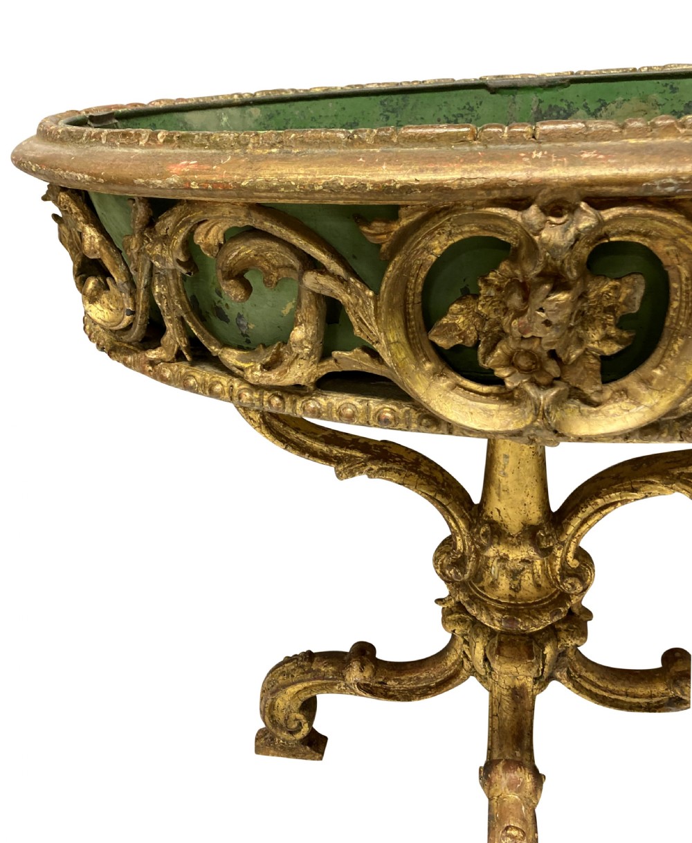 An early 19th-century carved giltwood circular jardiniere featuring scrollwork moulding, a green painted metal liner, and a sculpted tripod base. View VIII