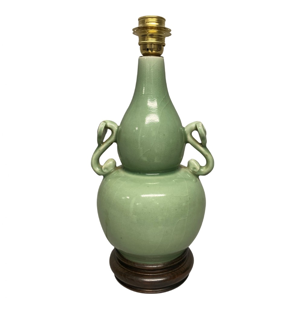 A Chinese pale green celadon ceramic double gourd vase lamp featuring twin scroll handles mounted on a dark wooden base with a brass light fitting.