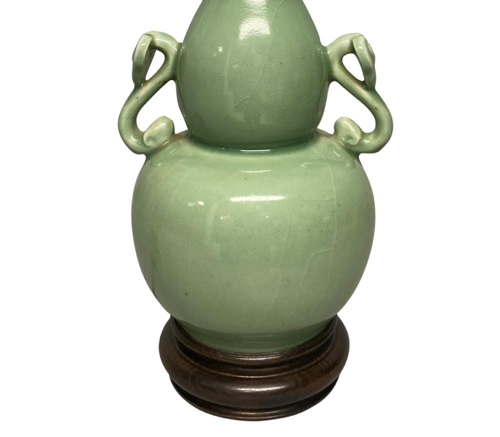 A Chinese pale green celadon ceramic double gourd vase lamp featuring twin scroll handles mounted on a dark wooden base with a brass light fitting. View V
