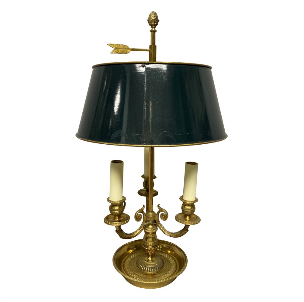 A French gilt brass bouillotte lamp with three candle-style light sockets and a dark green painted metal shade mounted on a central stem with an arrow key motif.