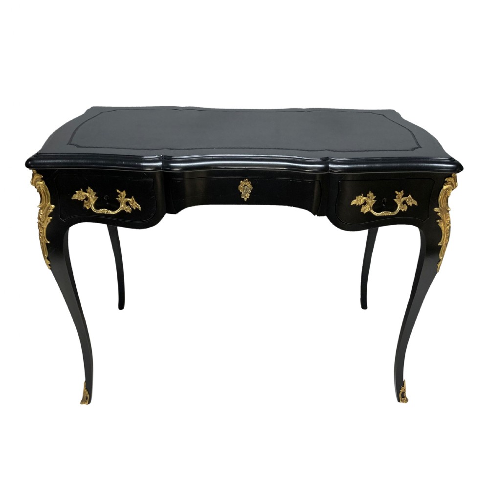 A Louis XV style black lacquered writing table with cabriole legs, an inset leather surface, and ornate gilt bronze corner mounts.