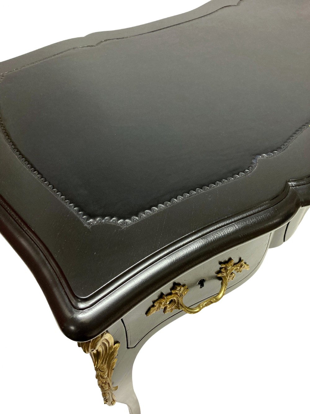 A Louis XV style black lacquered writing table with cabriole legs, an inset leather surface, and ornate gilt bronze corner mounts. View IV