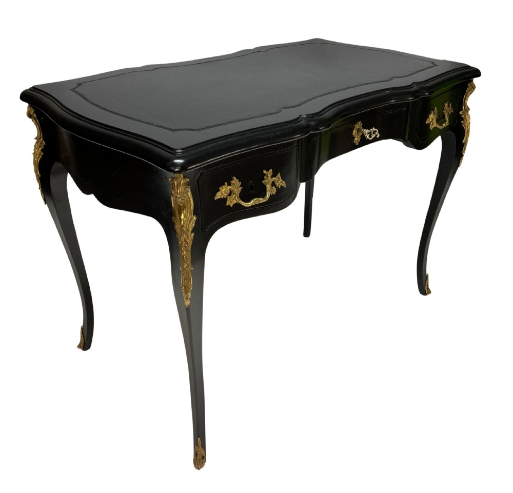 A Louis XV style black lacquered writing table with cabriole legs, an inset leather surface, and ornate gilt bronze corner mounts. View V